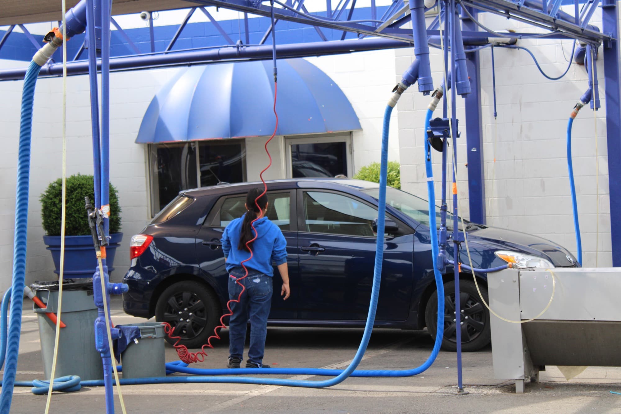 A Jeff's attendant hand-drying a car under the wash canopy